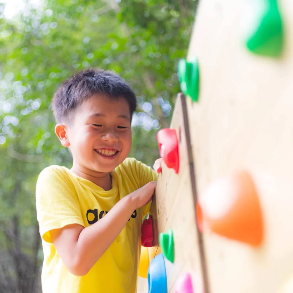 ボルダリングの壁をのぼる子ども