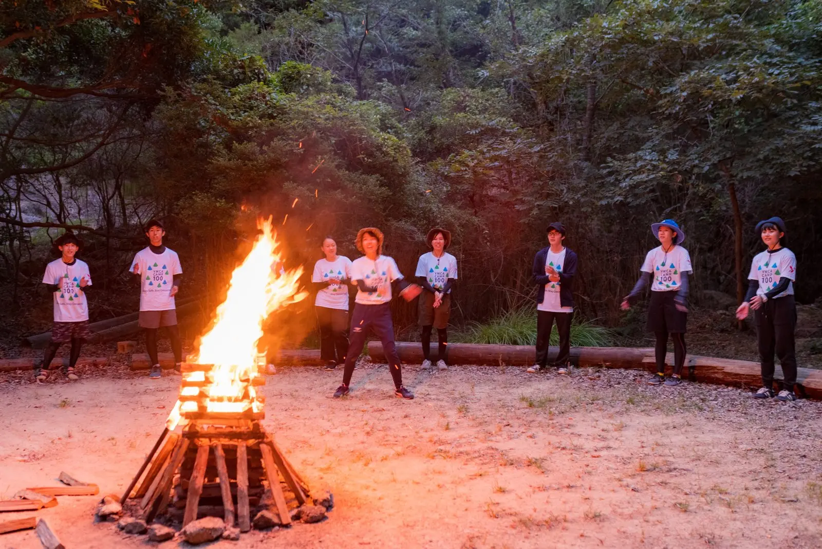 夕暮れの森で、キャンプファイヤーを囲む