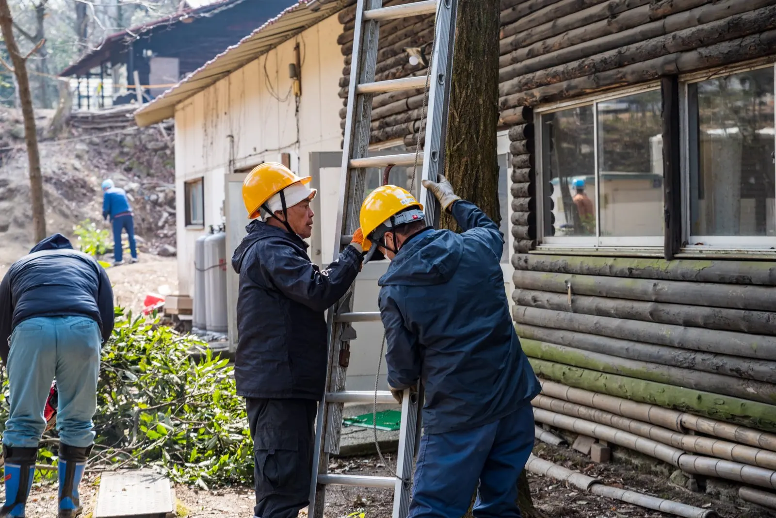 建物の脇ではしごを支え合う