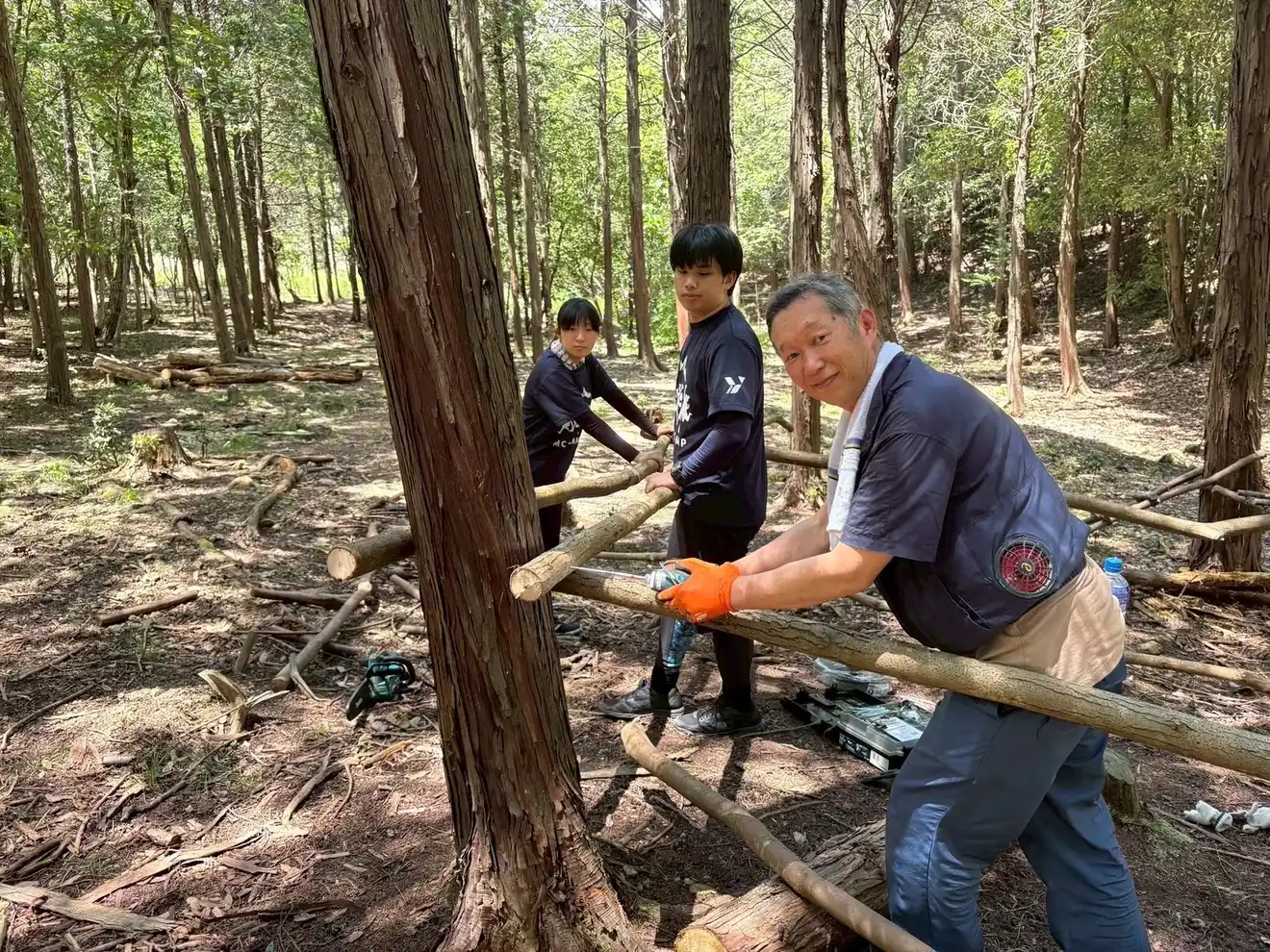 世代のちがう大人たちが、丸太を運ぶ